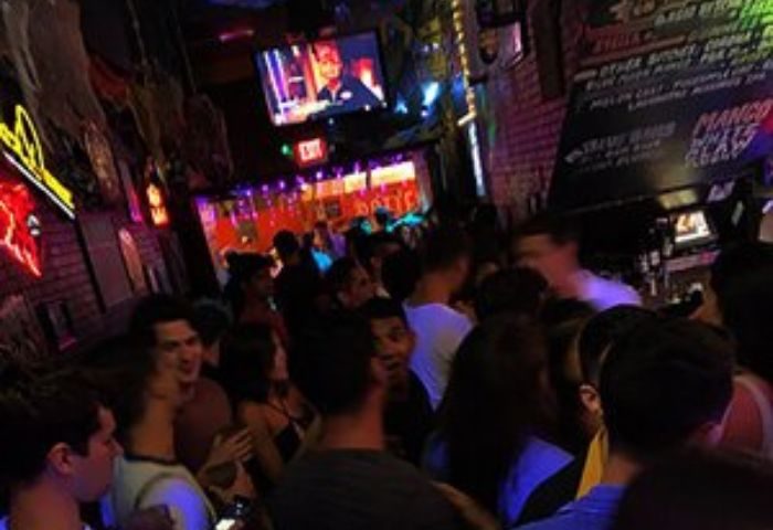 Crowded scene inside The Bayou, a gay bar. Neon lights, TV screen, and people mingling. Gay travel experience. The-Bayou-Experience.jpg