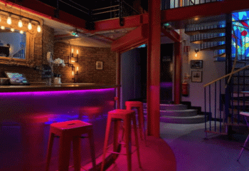 Interior of The Boilerhouse gay sauna in Dublin. Bar with red stools, stairs, and spiral staircase. Gay travel advice.