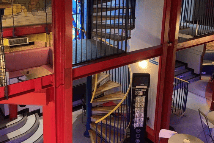 Interior view of The Boilerhouse gay sauna in Dublin. Red beams, spiral staircase, and elevator panel are visible. Gay travel.