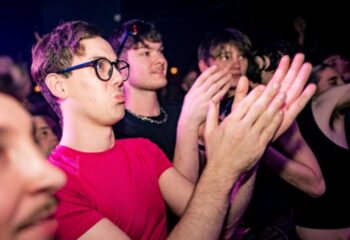 Gay men at The Brewers Manchester, clapping. Nightlife scene, travel advice. Crowd enjoying the show, vibrant atmosphere.