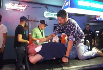 Gay bar scene: Man kneels on another man lying on a pool table at The Broadway Bar. Nightlife, dance, drinks, and travel advice.