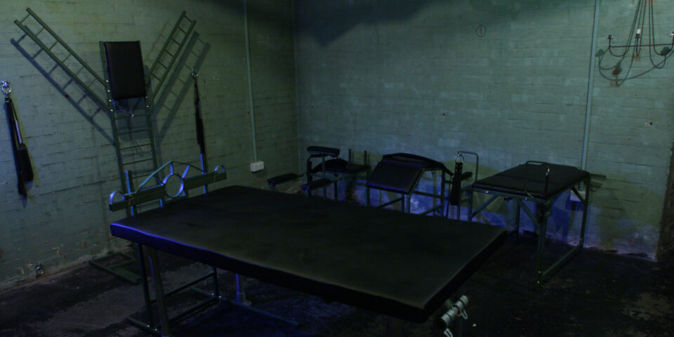 The Bunker London: Private appointment only gay cruise club. Dark room interior with various apparatus and furniture.