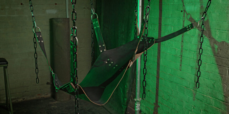 The Bunker London Gay Cruise Club interior. Private appointment only. Leather sling suspended by chains in a dungeon-like setting.