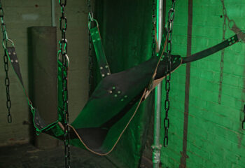 The Bunker London Gay Cruise Club interior. Private appointment only. Leather sling suspended by chains in a dungeon-like setting.