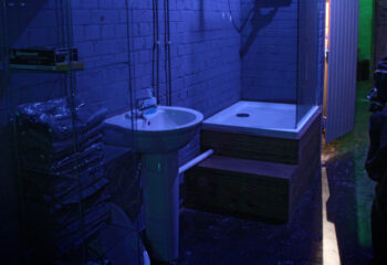 The Bunker London interior. Sink, shower, and figure in a dark room. Gay cruise club, private appointment only. Gay travel advice.