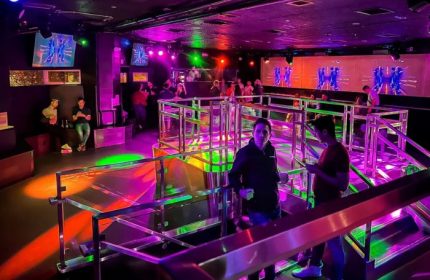The Cafe Night Club in San Francisco. Gay bar interior with colorful lighting, DJ, dance floor, and men socializing. Gay nightlife travel.