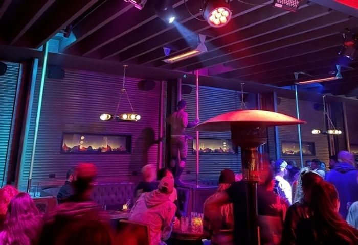The Chapel @ The Abbey dancefloor. Gay bar with a dancer on a pole, purple lighting, and people enjoying the night life. Gay travel advice.