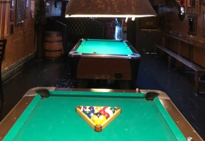 Interior of The Cinch Saloon, a gay bar in San Francisco. Pool tables, bar stools, and a barrel are visible, creating a classic saloon vibe.