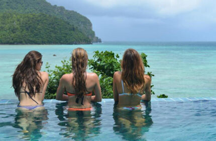 Cobble Beach Hotel, Koh Phi Phi. Women in rooftop pool overlooking beachfront. Cheap, gay-friendly hotel. Tropical vacation vibes.