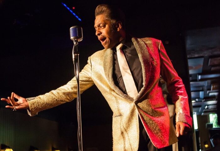Drag show at The Cock Tavern, a cool gay bar in London. Performer in a gold jacket sings into a microphone on stage. LGBTQ+ nightlife.
