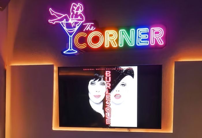 The Corner Bar, a gay place in Puerto Vallarta, with neon sign and Burlesque movie poster on screen. Gay travel advice.