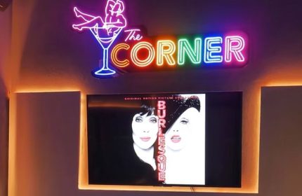 The Corner Bar, a gay place in Puerto Vallarta, with neon sign and Burlesque movie poster on screen. Gay travel advice.