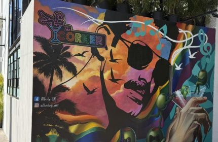 Mural art at The Corner Bar, a gay-friendly music venue in Puerto Vallarta. Features a face, palm trees, and cocktail elements.