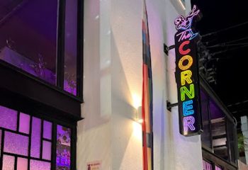 The Corner Bar neon sign, a gay place in Puerto Vallarta, Mexico, with colorful lights and a cocktail glass icon, inviting gay travelers.