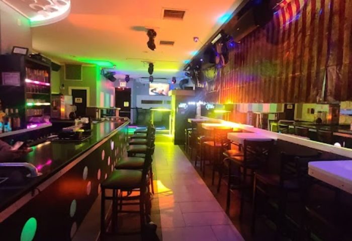 Interior of The Deep End Resto-Bar in New York. Gay bar's colorful lighting, bar stools, and a lively atmosphere. Gay travel advice.