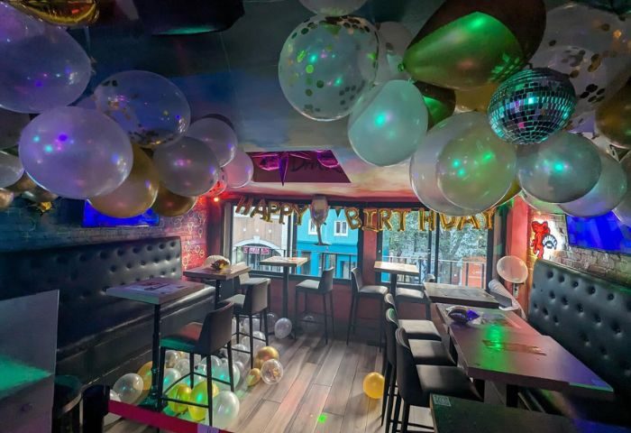 Toronto bar interior decorated for a birthday. Balloons, tables, and chairs fill the space. A fun spot for gay men to travel to.