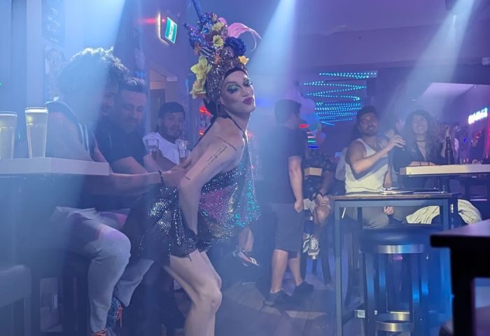 Drag queen performs at The Drink, a gay pizza bar in Toronto. Patrons watch the show in the bar's smoky, atmospheric interior.