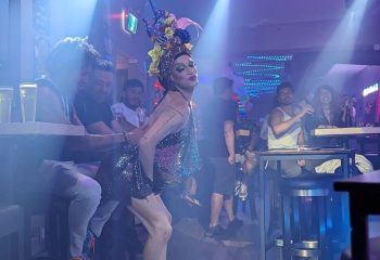 Drag queen performs at The Drink, a gay pizza bar in Toronto. Patrons watch the show in the bar's smoky, atmospheric interior.