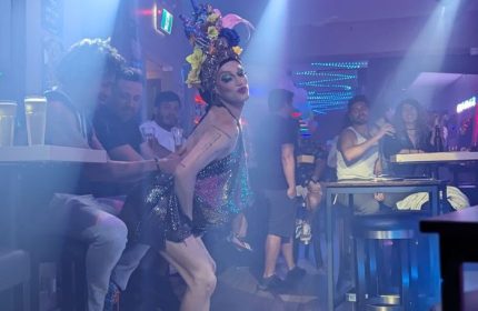 Drag queen performs at The Drink, a gay pizza bar in Toronto. Patrons watch the show in the bar's smoky, atmospheric interior.
