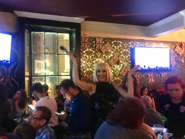 The Duke of Wellington gay bar in London: drag queen performing for a crowd. Union Jack decor. Gay travel advice.