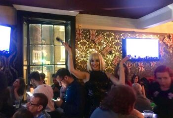The Duke of Wellington gay bar in London: drag queen performing for a crowd. Union Jack decor. Gay travel advice.
