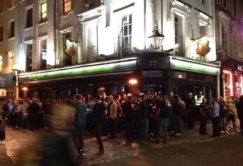 The Duke of Wellington gay bar in London. Crowd of men outside the pub at night. Gay travel destination.
