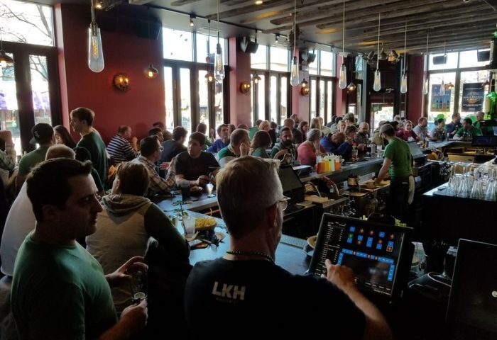 The Elixir Lounge gay bar in Chicago is packed with people. Bartender uses a screen. Great spot for gay men travel advice.