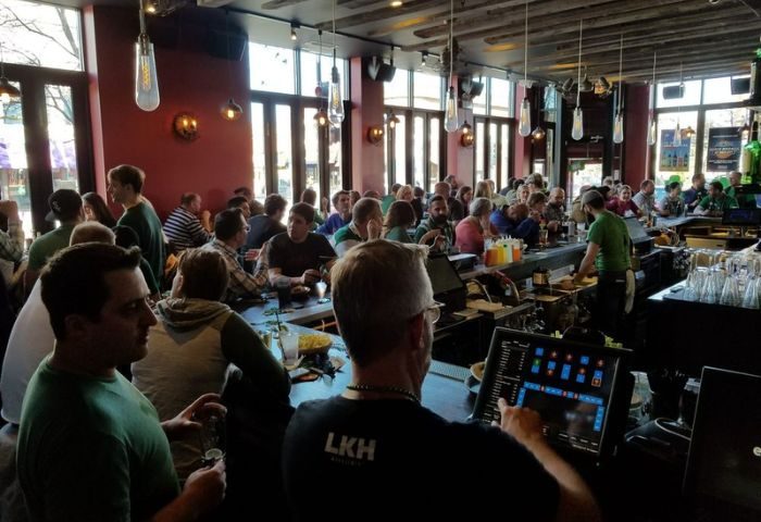 The Elixir Lounge gay bar in Chicago is packed with people. Bartender uses a screen. Great spot for gay men travel advice.