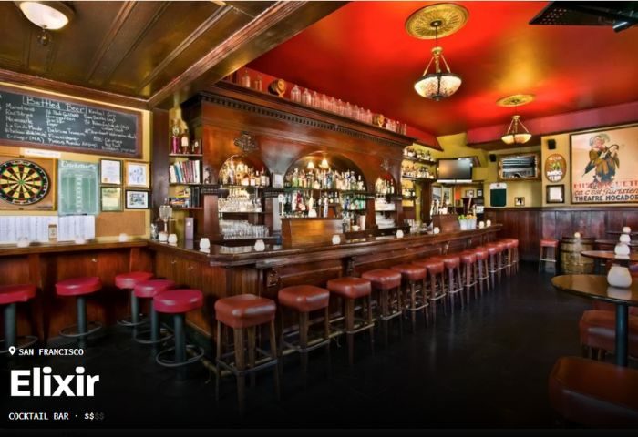 Interior of Elixir Lounge, a gay bar in Chicago. Long wooden bar with stools, dart board, and vintage decor. Gay travel advice.
