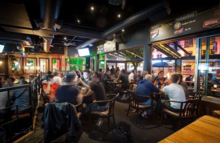Interior of The Fountainhead Pub in Vancouver. People sit at tables in the gay-friendly bar. Nightlife travel advice.