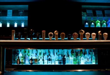 The Fountainhead Pub in Vancouver bar. Bottles and taps are backlit with blue light. Gay travel advice.