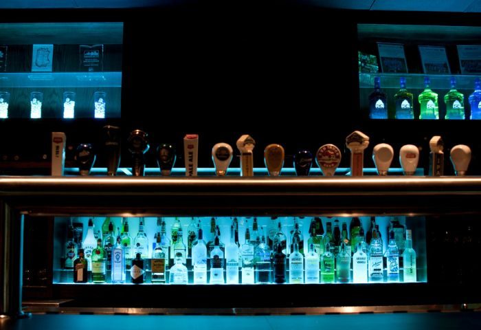The Fountainhead Pub in Vancouver bar. Bottles and taps are backlit with blue light. Gay travel advice.