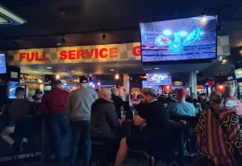 Gay bar, The Garage, in Las Vegas. Men watch a game on TV at the bar. Full service sign. Gay travel advice for Vegas.