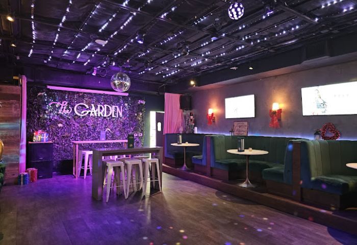 Interior of The Garden Las Vegas gay bar, featuring booths, tables, bar stools, disco balls, and decorative lighting. Gay travel advice.