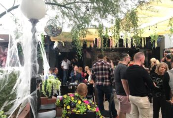 The Garden Las Vegas gay bar scene. Outdoor patio with men, disco ball, and Halloween decor. Gay travel advice for nightlife.