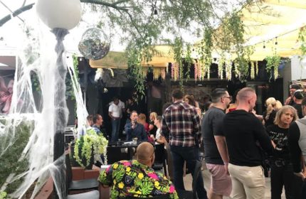 The Garden Las Vegas gay bar scene. Outdoor patio with men, disco ball, and Halloween decor. Gay travel advice for nightlife.