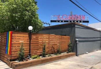 The Garden Las Vegas gay bar exterior. Rainbow flag on wood fence. Neon sign. Gay travel destination.
