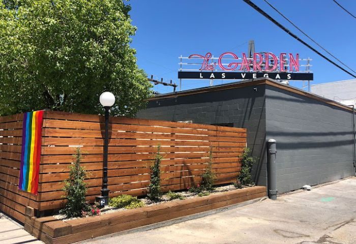 The Garden Las Vegas gay bar exterior. Rainbow flag on wood fence. Neon sign. Gay travel destination.