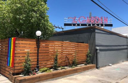 The Garden Las Vegas gay bar exterior. Rainbow flag on wood fence. Neon sign. Gay travel destination.