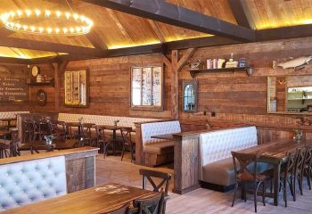 The Glenwood Gay Bar in Chicago: Rustic interior with wood walls, booths, tables, chairs, and a unique chandelier. Gay travel advice.