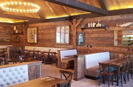 The Glenwood Gay Bar in Chicago: Rustic interior with wood walls, booths, tables, chairs, and a unique chandelier. Gay travel advice.