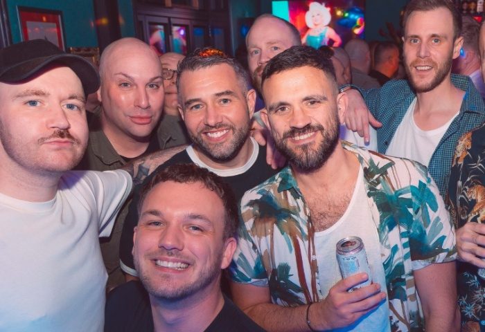 A group of gay men smiling at The Goose, Manchester. Gay travel advice. Manchester's gay scene. Nightlife.
