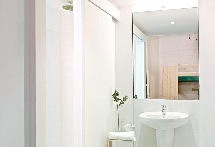 Bathroom at The Hat Hostel Madrid, a top gay hostel near Gran Via. Features a shower, sink, mirror, and minimalist decor. Ideal for gay couples.