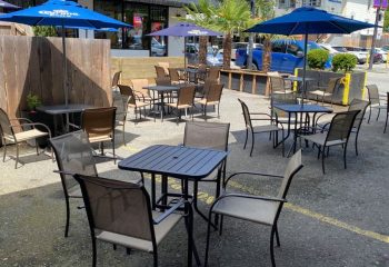 Outdoor patio at The Junction Pub in Vancouver. Tables and chairs under blue umbrellas provide a relaxing space for gay travelers.