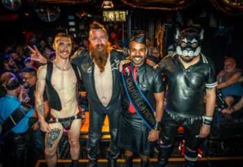 The Laird Melbourne event: four gay men in leather gear, one in a puppy mask, posing at a gay bar. Leather and fetish scene.