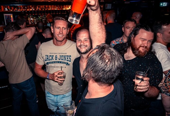 Gay men enjoying drinks at The Laird Melbourne, a gay bar. Men drinking, socializing, and having fun in a bar setting. Nightlife scene.