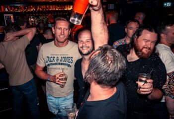 Gay men enjoying drinks at The Laird Melbourne, a gay bar. Men drinking, socializing, and having fun in a bar setting. Nightlife scene.