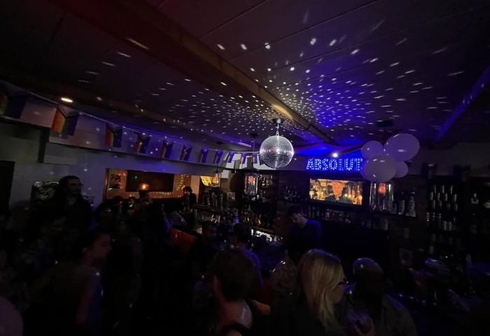 Inside The Lodge at O'Gradys gay bar in Toronto. Disco ball, rainbow flags, & Absolut sign. Gay travel advice for men.