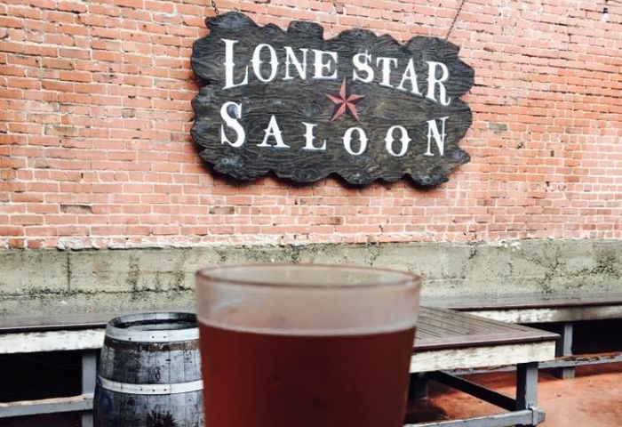 Lone Star Saloon in San Francisco: A gay bar with a beer, barrel, & wooden sign on a brick wall. A popular spot for gay men's travel.