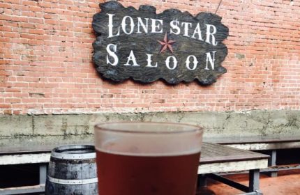 Lone Star Saloon in San Francisco: A gay bar with a beer, barrel, & wooden sign on a brick wall. A popular spot for gay men's travel.